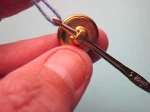 Pulling a loop of yarn through the button shank