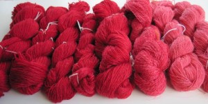 Hand-spun skeins of Romney wool in a series of red shades