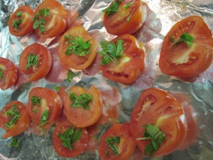 Halved tomatoes sprinkled with seasoning and chopped basil