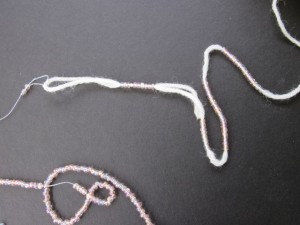 Continue sliding beads from pre-strung thread onto project yarn/thread
